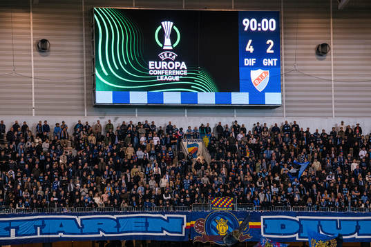 A big display shows the score behind the supporters of