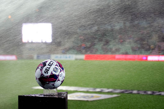 En boll blir blöt av bevattning innan fotbollsmatchen i