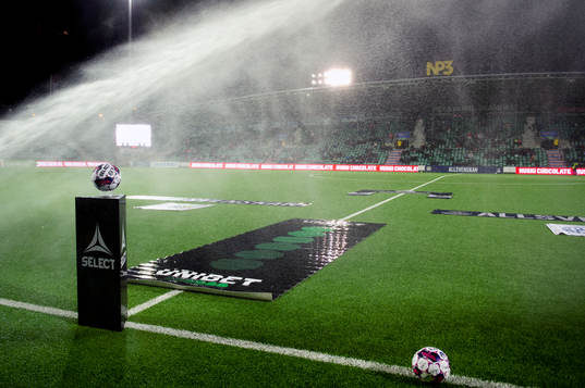 En boll blir blöt av bevattning innan fotbollsmatchen i