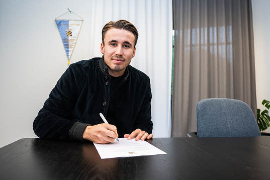 Anders Trondsen signerar kontraktet i samband med att han