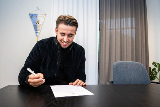 Anders Trondsen signerar kontraktet i samband med att han
