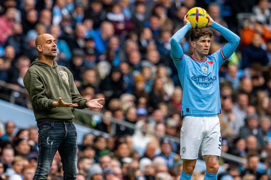 Pep Guardiola, manager of Manchester City, and John Stones
