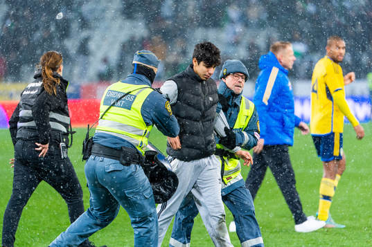 Security personel hold a pitch invader