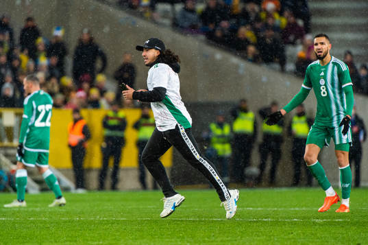 A pitch invader next to Nabil Bentaleb of Algeria