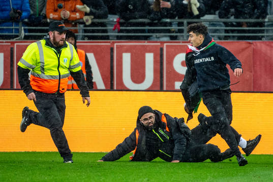 Security personel chase a pitch invader