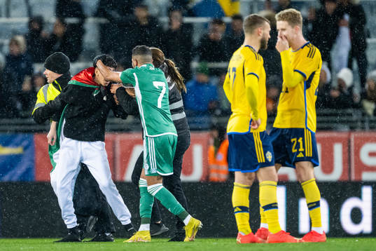 Security personell hold a pitch invader next to Riyad