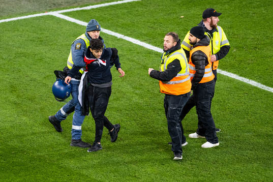 Security personell hold a pitch invader