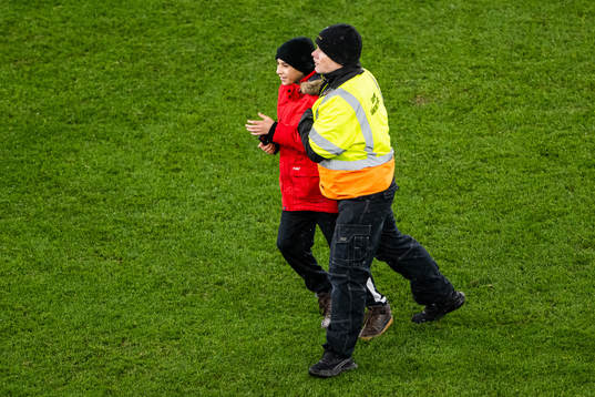 Security personell hold a pitch invader