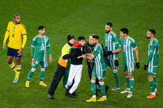Security personell hold a pitch invader