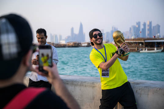 A man poses with a trophy replica at the Corniche Promenade