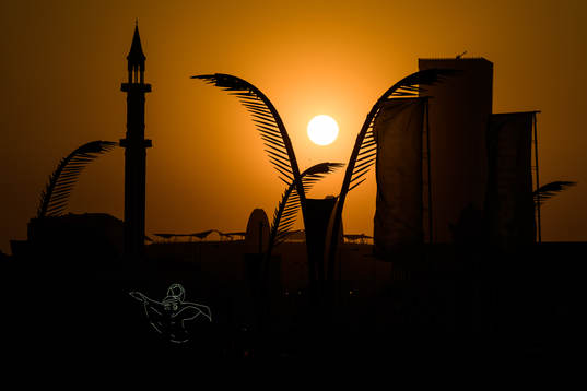 A light display of mascot La'eeb at sunset