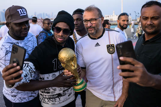 People pose with a trophy replica at the Corniche Promenade
