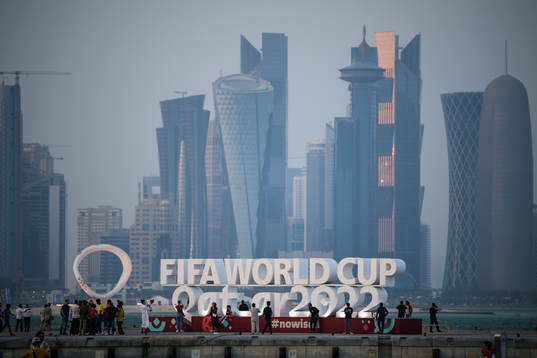 People pose in front of a World Cup logo at Corniche