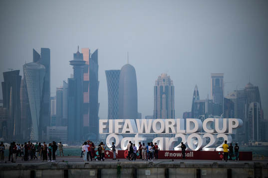 People pose in front of a World Cup logo at Corniche