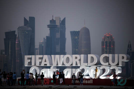 People pose in front of a World Cup logo at Corniche