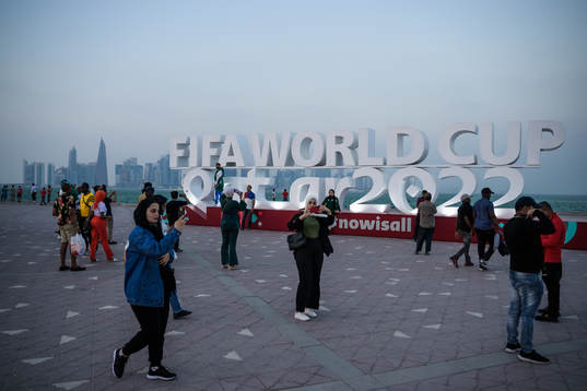 People pose in front of a World Cup logo at Corniche