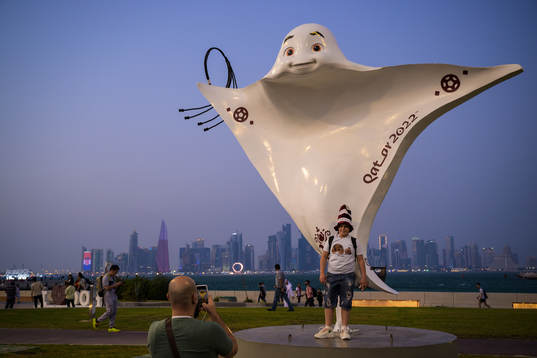 A boy poses in front of the mascot La'eeb