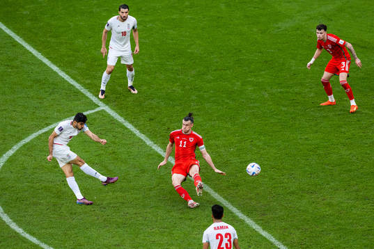 Mehdi Torabi of Iran shoots past Gareth Bale< of Wales