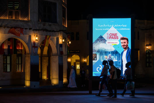 People walk past an ad with David Beckham