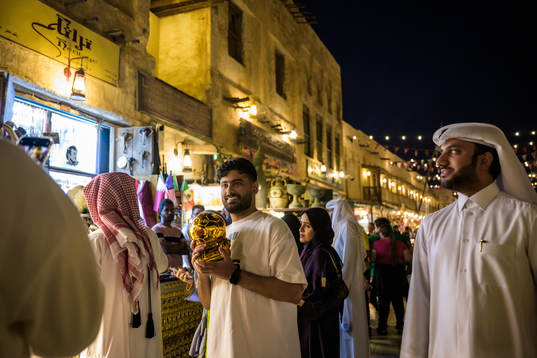 A man holds a golden football outside a store
