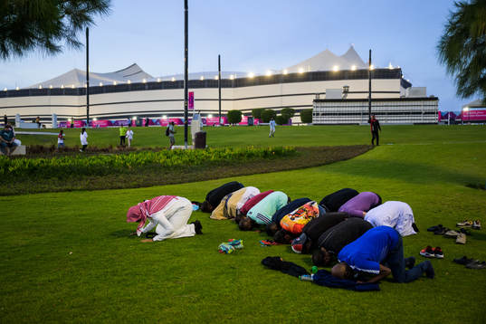 Men pray outside Al Bayt Stadium