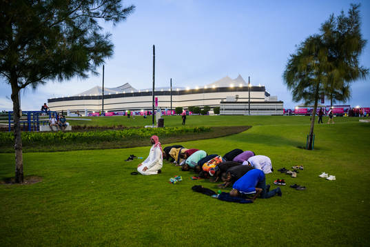 Men pray outside Al Bayt Stadium