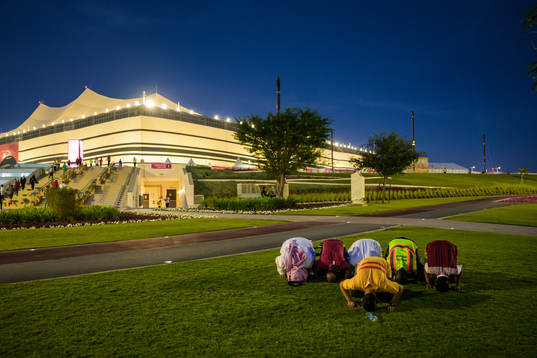 Men pray outside Al Bayt Stadium