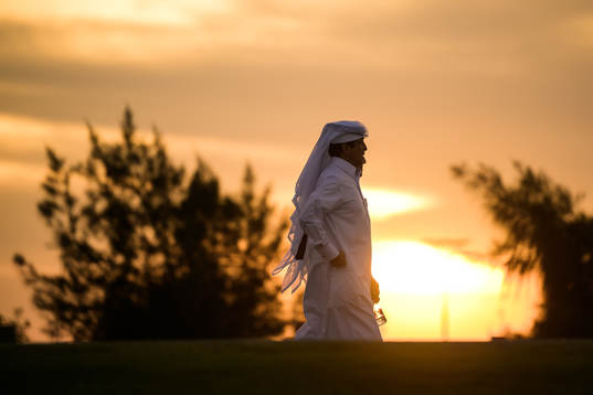 Men in Qatari clothing walk towards the arena