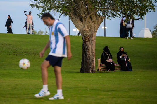 Two Qatari women see a man playing football