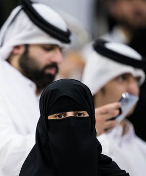 A woman wearing a niqab in front of two men in Qatari