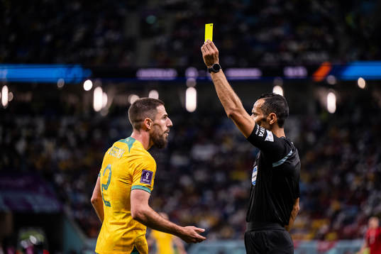Milos Degenek of Australia is shown a yellow card by