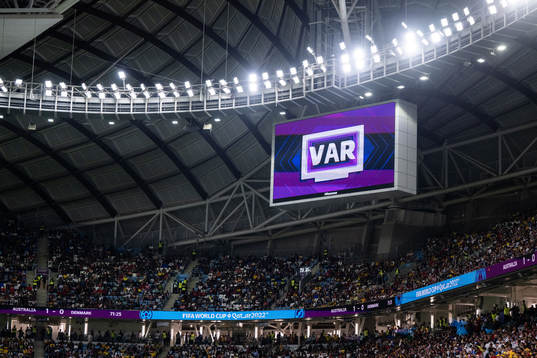 A big screen displays a VAR review message