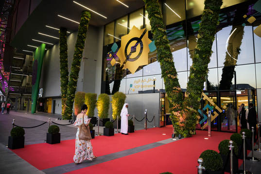 A woman walks at a red carpet to the VIP entrance