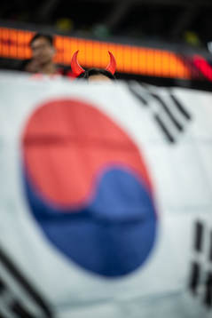 A fan of South Korea with devil horns in front of the South
