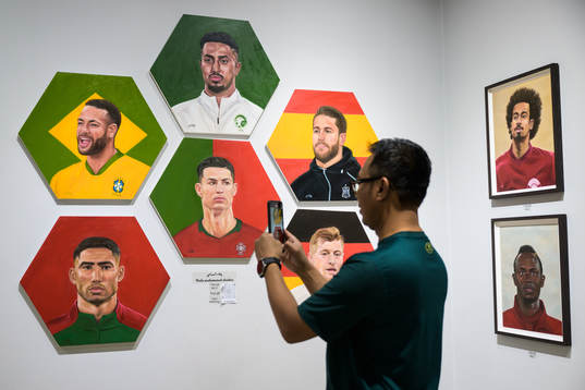 A man shoots video of paintings of football stars