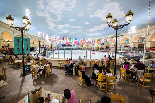People dine next to an indoor ice skating rink at Villaggio