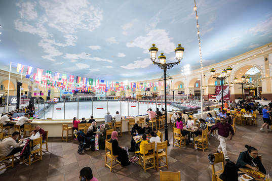 People dine next to an indoor ice skating rink at Villaggio
