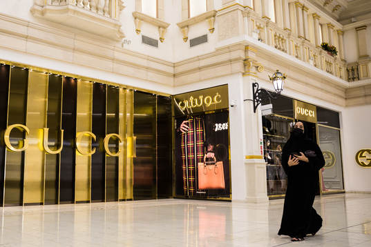 A woman walks past a Gucci store at Villaggio Mall