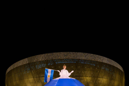 A performer waves an Argentinian flag outside Lusail Stadium
