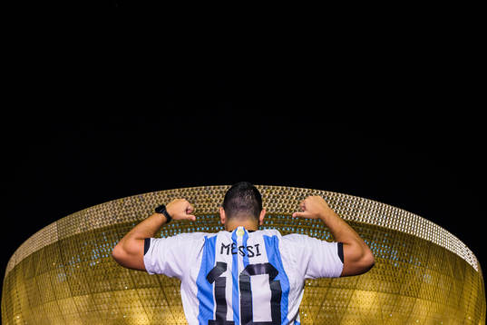 A man with a Lionel Messi jersey poses in front of Lusail