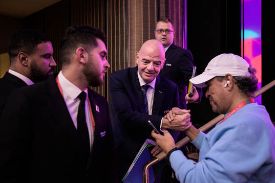 A member of media greets Gianni Infantino, president of FIFA