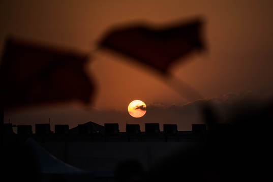 People wave Moroccan flags at sunset