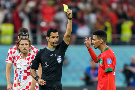 Referee Abdulrahman Al Jassim shows a yellow card to