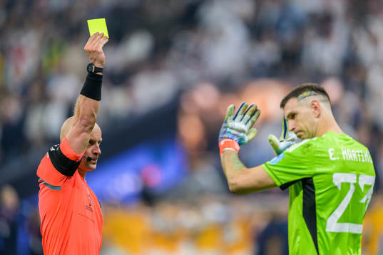 referee Szymon Marciniak shows goalkeeper Emiliano Martinez