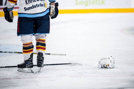 Hockeyhjälm och klubbor på isen