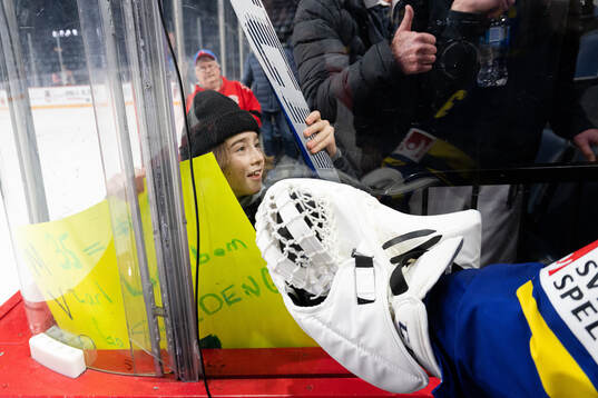 A fan receives a signed stick from goaltender Carl Lindbom