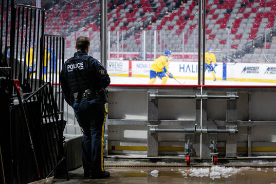A police officer watches a practice session with Team Sweden