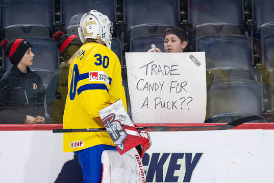 Goaltender Marcus Brännman of Sweden trades a puck for
