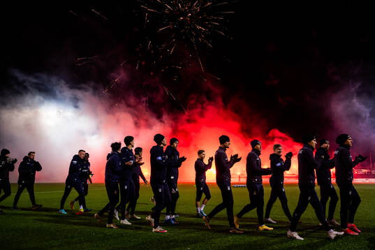 Spelarna gör entré medan supportrarna bränner bengaler