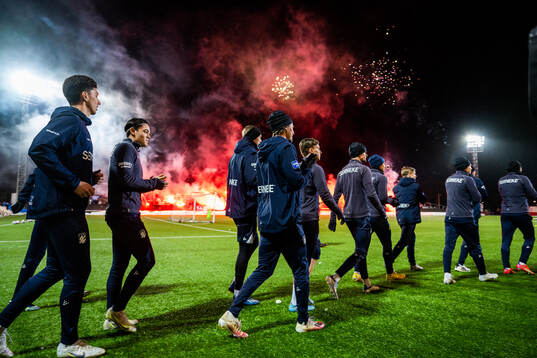 Spelarna gör entré medan supportrarna bränner bengaler